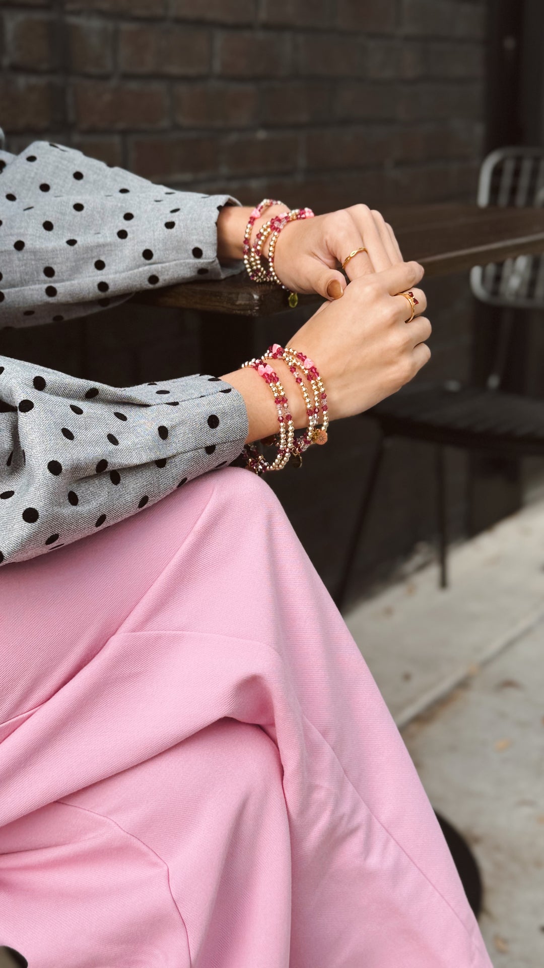 Person wearing a polka dot sweater and pink valentines opal bracelets on a blurred background