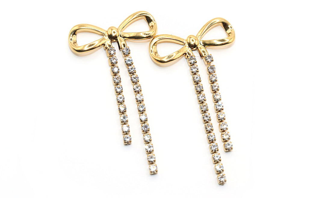 Gold bow-shaped earrings with rhinestone details on a white background