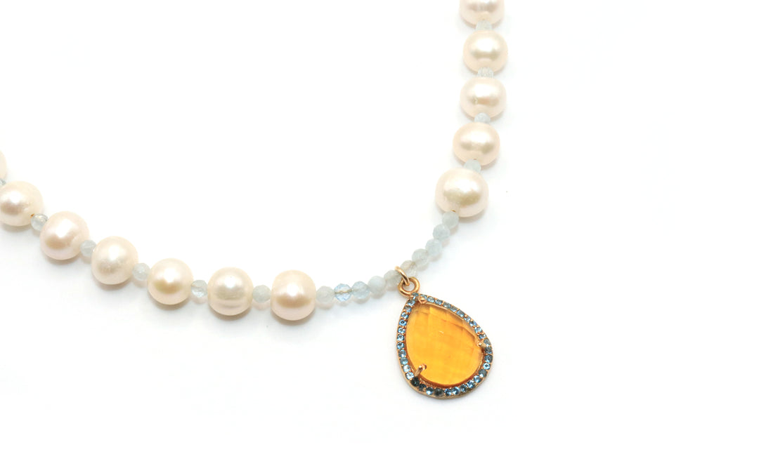 Pearl necklace with a teardrop-shaped citrrine pendant on a white background