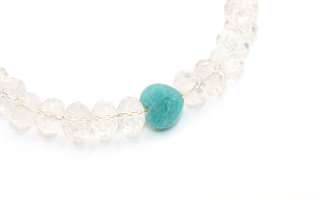 Necklace with clear beads and a turquoise stone on a white background