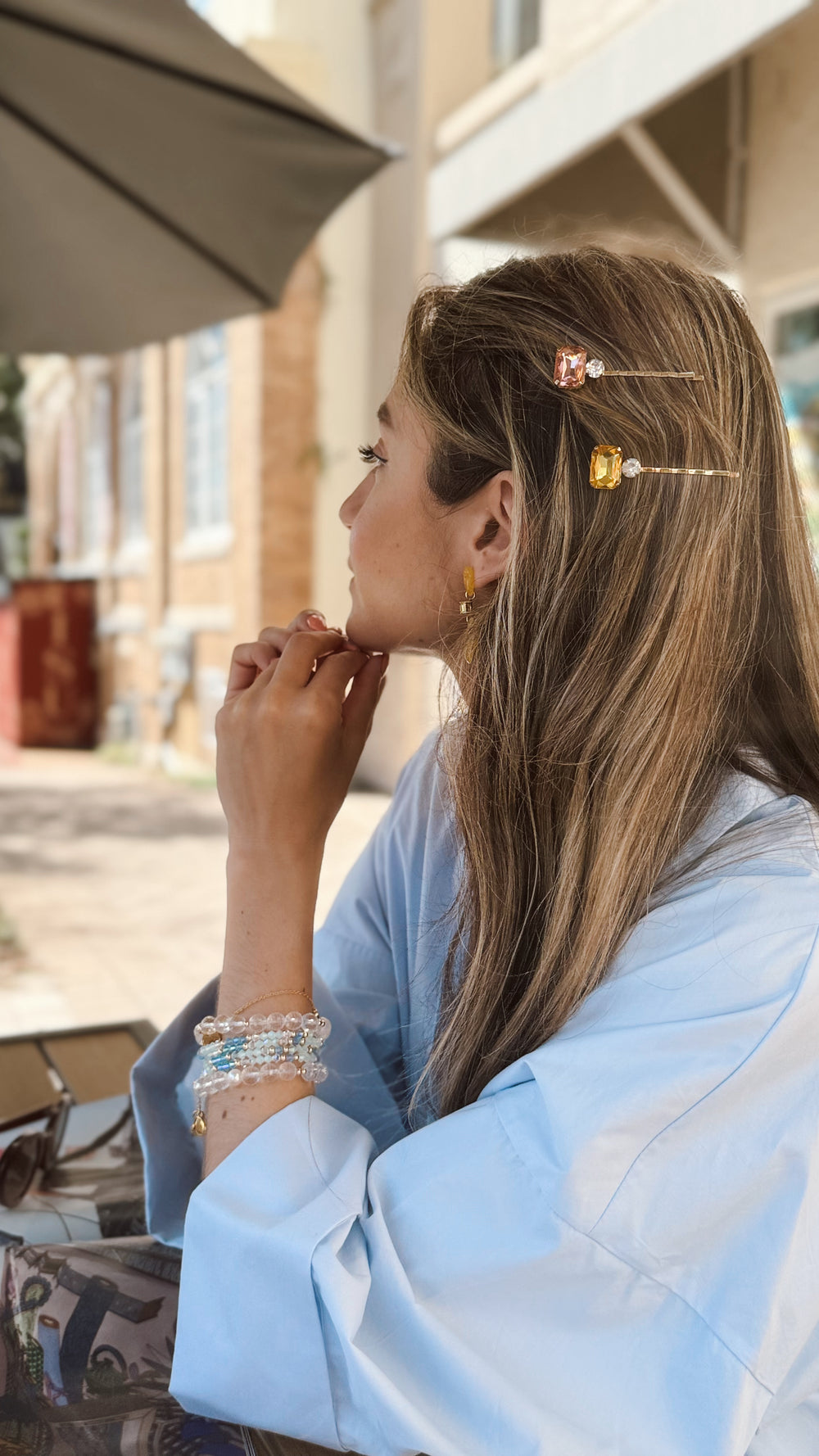 Woman with decorative hairpins and bracelets sitting outdoors