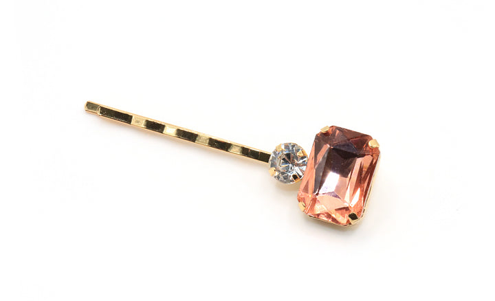Gold hairpin with a pink gemstone on a white background